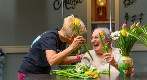Green House home staff member cutting tulips with a smiling elder